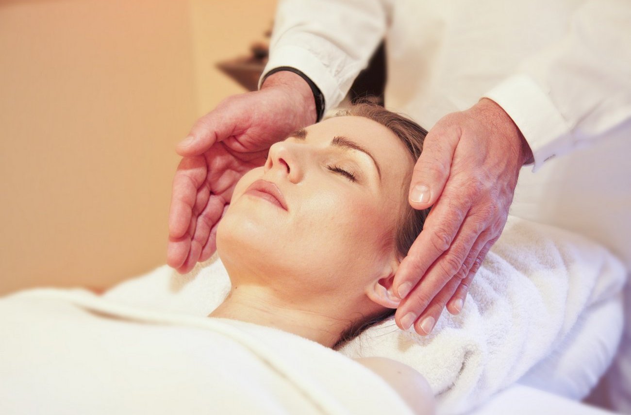 Reiki practicioner performing reiki on woman's head